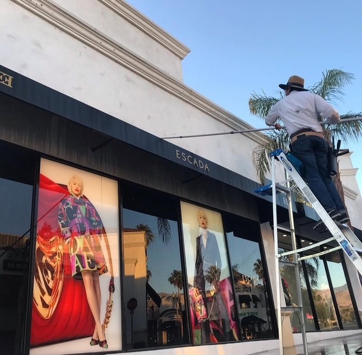 Technician on a ladder washing a storefront awning