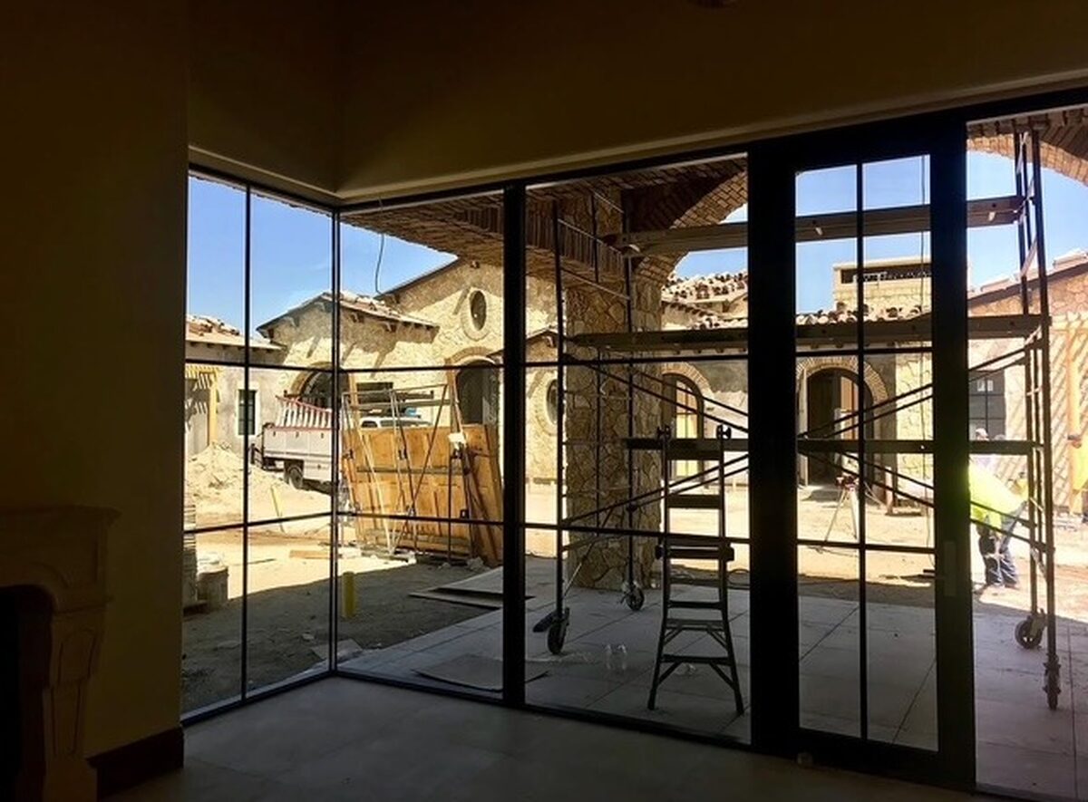 New-build steel-framed glass before the clean — construction dust on every pane