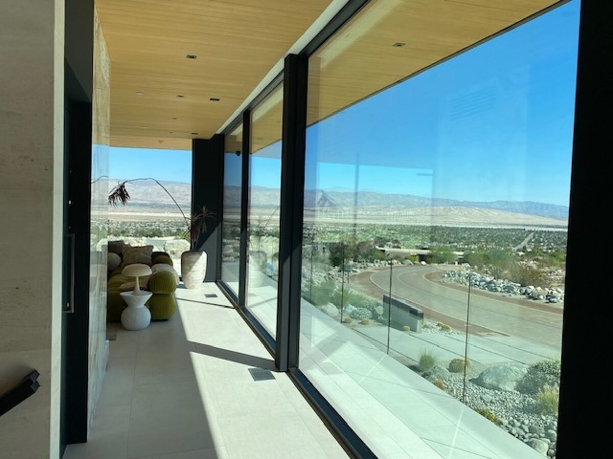 Looking out through floor-to-ceiling glass at a desert valley and mountains