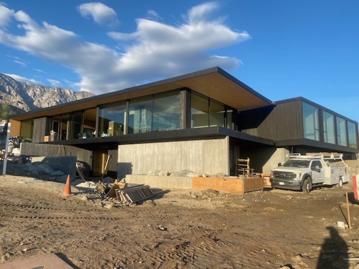 New-build glass house under a bright desert sky, mountains behind