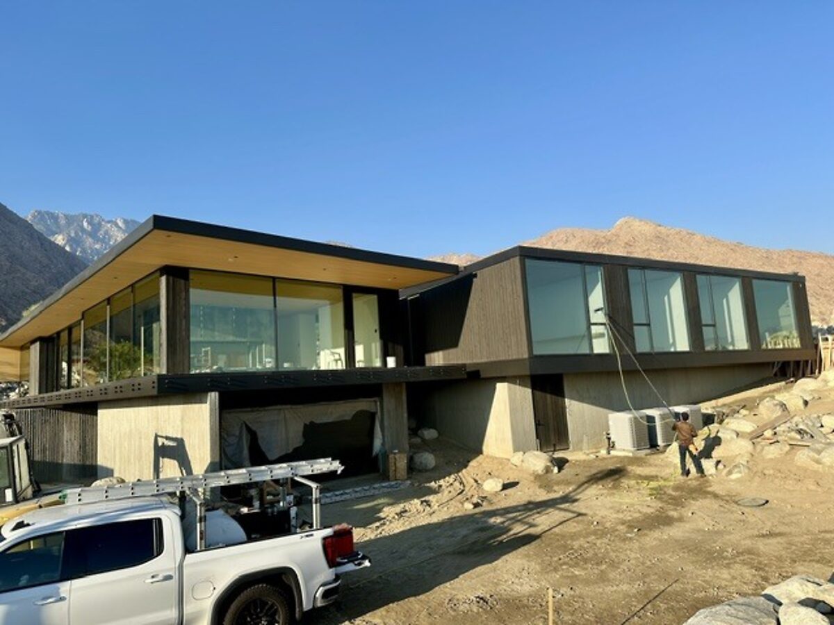 New-build glass wall with the crew's truck on site, mountains behind