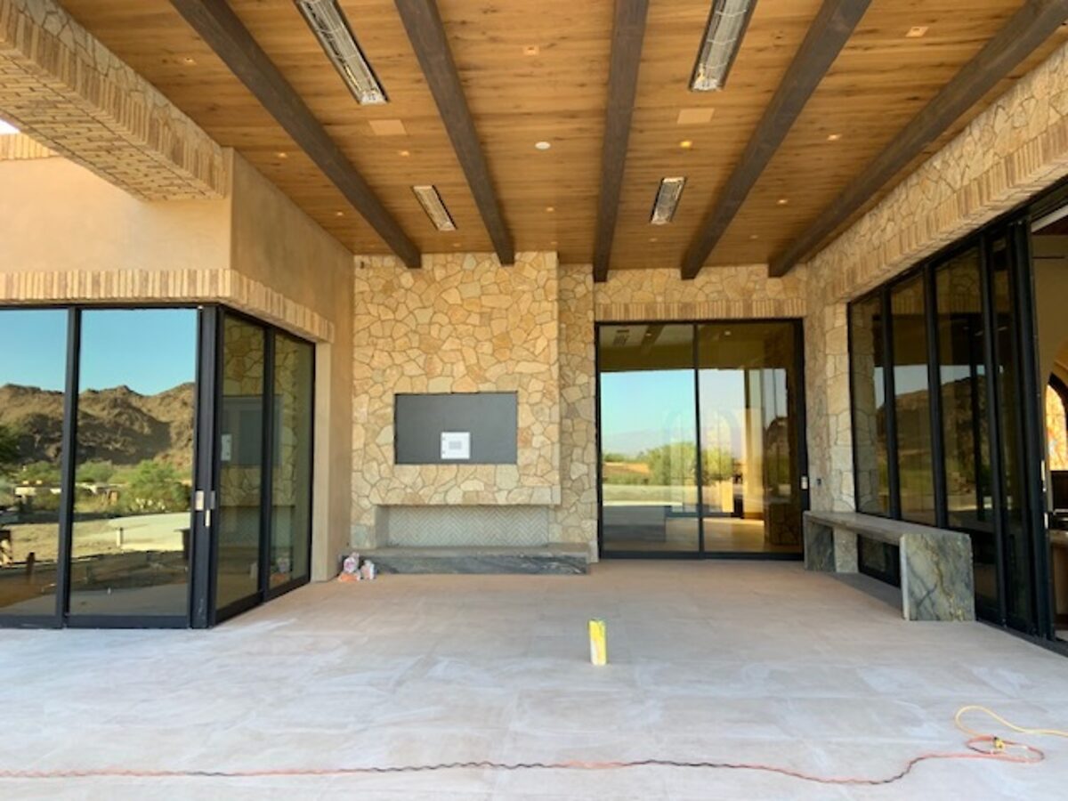 Covered patio of a new build mid-finish, stone walls and glass still dusty from the trades