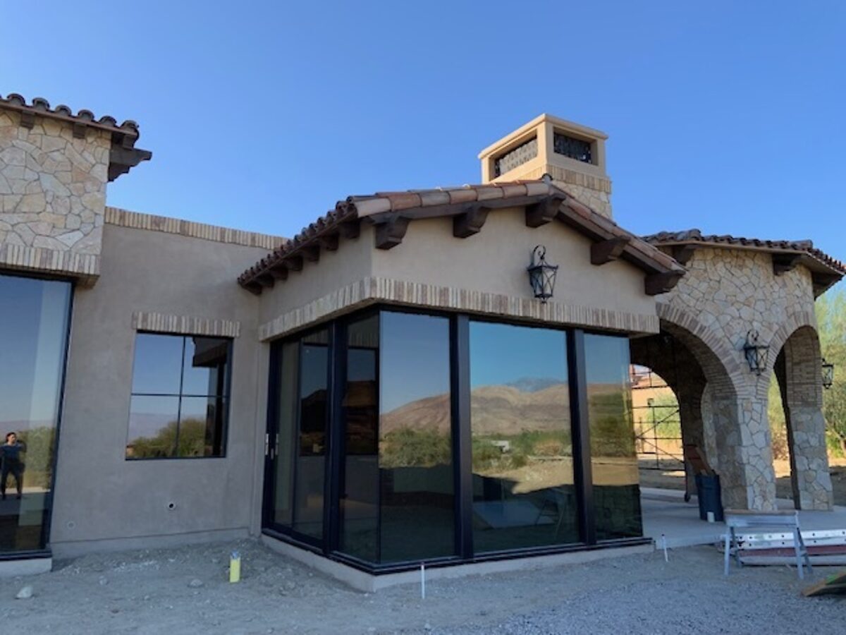 Stone and stucco Spanish house with corner glass, dirt lot still unfinished