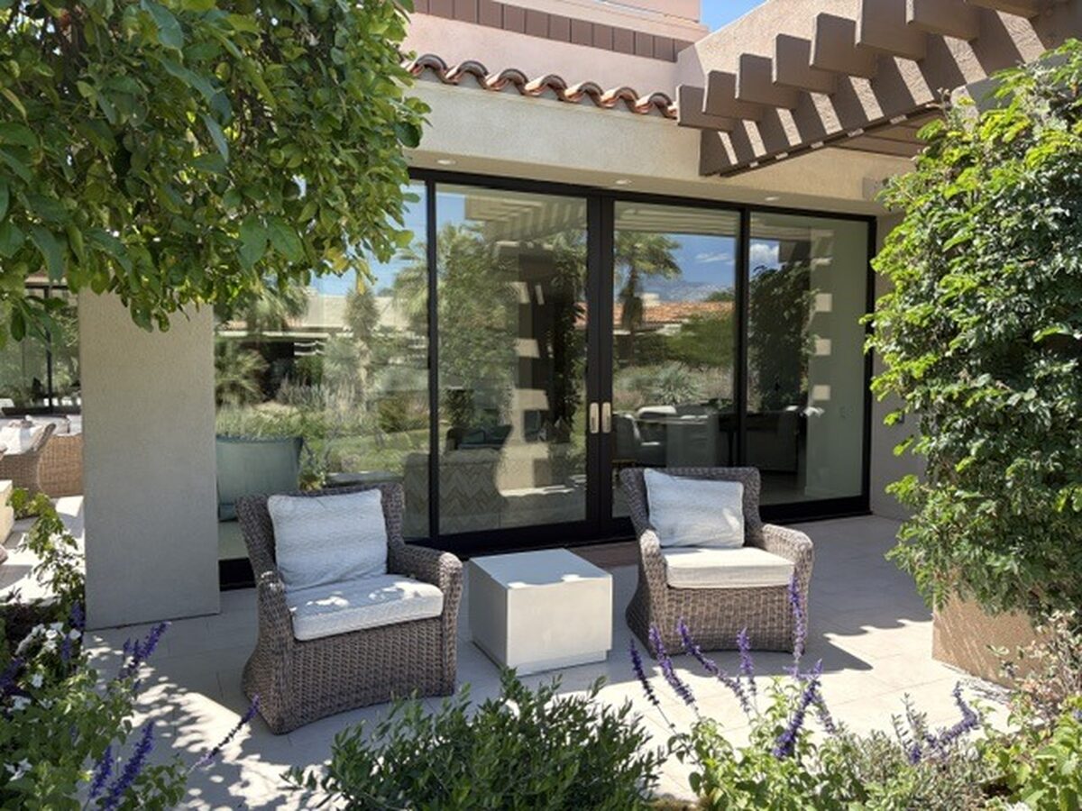 Patio with sliding glass doors, wicker chairs, and desert planting